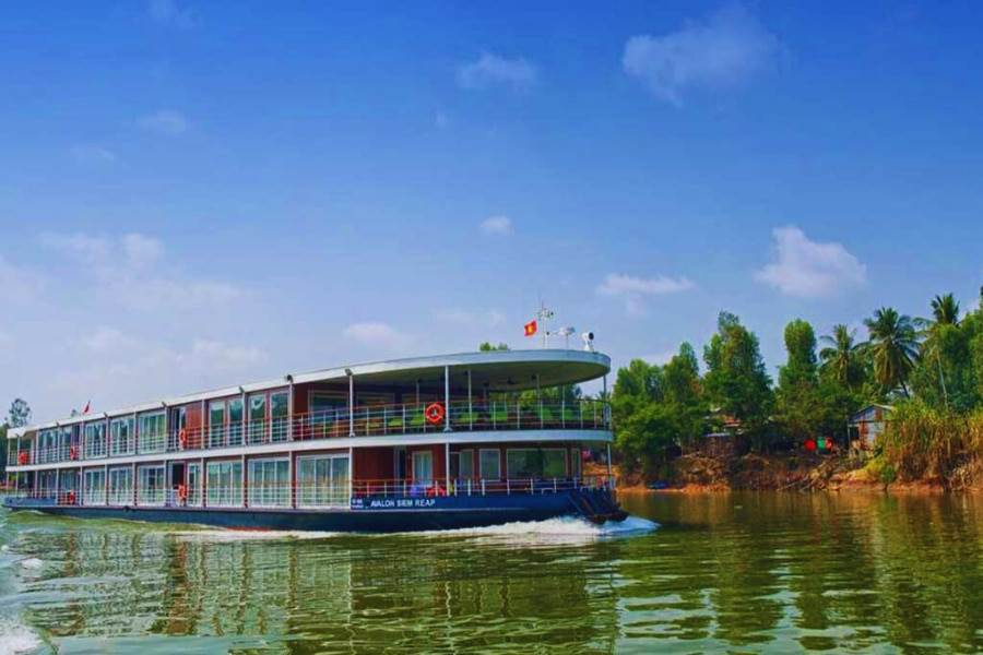 Mekong River Cruise ship gliding through calm waters near rural riverbank Vietnam